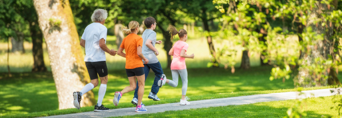 Family jogging on a paved path lined with trees